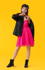 Fashionable young woman wearing mask on color background