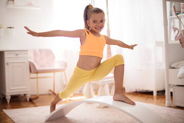 Little girl doing a workout in the bedroom at home.