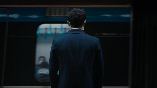 Back view of businessman waiting for subway on platform