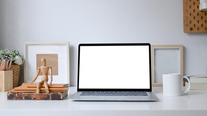Front view computer laptop with blank screen and office supplies on white table.