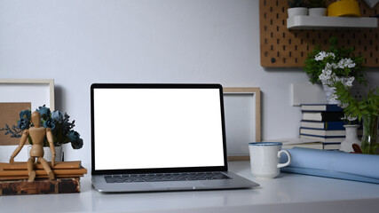 A computer laptop with empty screen and office supplies on white table.