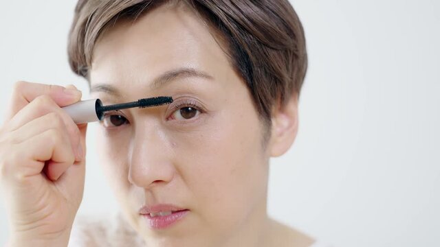 眉毛を整えるミドル女性　アイブロウブラシ　化粧品　コスメ