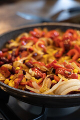 Mexican style stir fry, in a non stick pan on gas stove. The food inside the pan is with bell pepper, corn, unions and kidney beans.