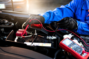 Technician uses multimeter voltmeter to check voltage level in car battery. Service and Maintenance car battery. - obrazy, fototapety, plakaty