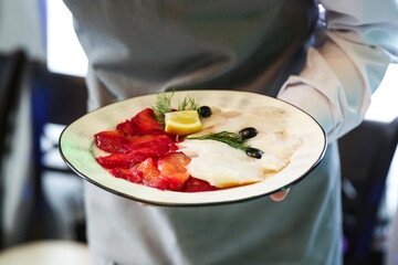 the waiter is holding a plate with salt fish slices