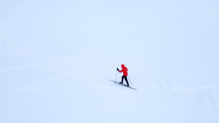 Naklejka na ściany i meble Cross country skier traveling across a snow covered arctic tundra in the high mountains on a cold winters day.