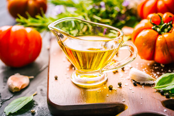 Olive oil, tomato and herbs on rustic cutting board