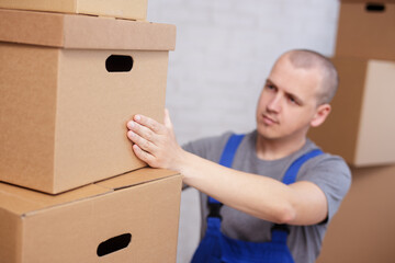 worker in uniform taking big box from shelf in warehouse