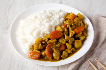 Homemade Japanese Chicken Curry  on a white plate on a white wooden background, side view.