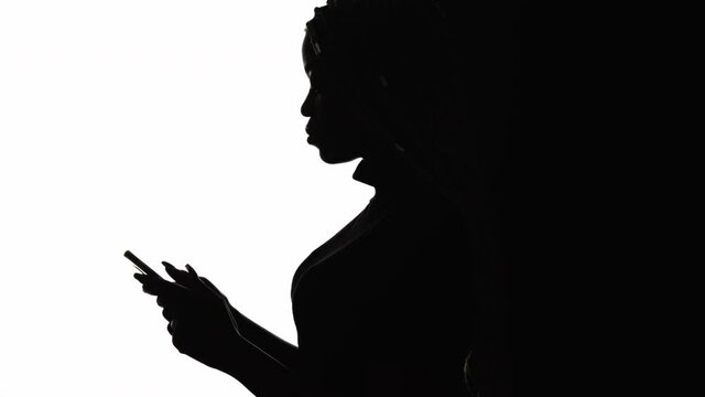 Mobile activity. Stressed silhouette woman. Chatting communication. Network opportunities. Concentrated black lady fast messaging on smartphone isolated white copy space.