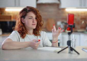 Technology and blogging concept. Redhair woman recording video concent for her blog at home