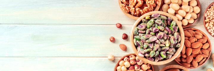 Nuts panorama with a place for text. Pistachios and other nuts in wooden bowls