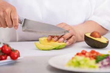 Female hands slicing avocado with a kitchen knife