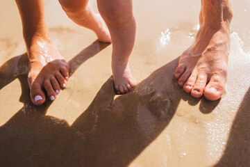 Legs of parents and child on sand. Happy loving family concept