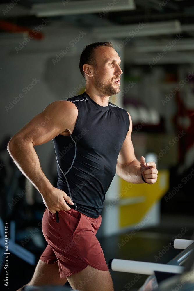 Wall mural Male athlete jogging on treadmill during gym workout.