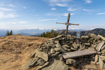 Cross on top of Herrenkogel and snow-capped mountains in the background