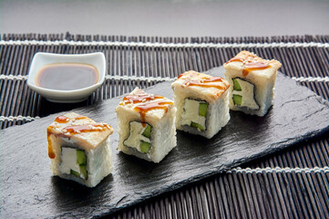 Philadelphia with a cucumber on a dark stone. Japanese sushi.