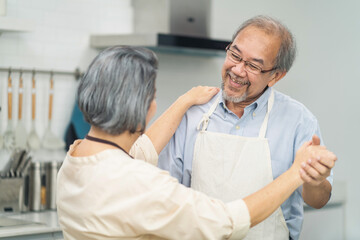 Asian senior couple dancing in the kitchen, Enjoy retirement life.