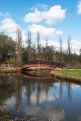 Fototapeta premium Wooden bridge over the river in the city park of Moscow, Sviblovo district. Spring landscape.