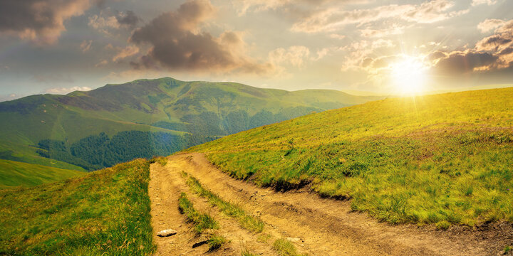 mountain landscape on a bright spring sunset. path through meadow in grass on the hill in evening light. wonderful weather with fluffy clouds on the sky. borzhava ridge of carpathians