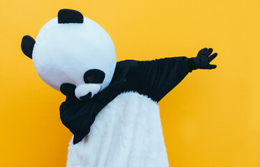 Person with panda costume dancing dab dance. Mascot character lifestyle concept on colored background