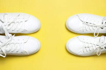 White sneakers on yellow background top view flat lay. Stylish youth women's leather sneakers, sports shoes, genuine leather footwear. Minimalistic shoe store advertising fashion style Shoe background