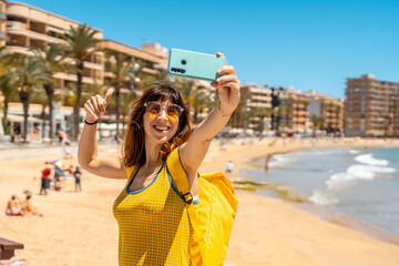 A young tourist taking a selfie with the phone at Playa del Cura in the coastal city of Torrevieja, Alicante, Valencian Community. Spain, Mediterranean Sea