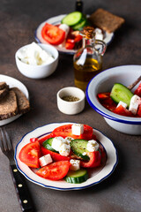 Healthy salad made from  vegetable feta cheese, cucumber, tomato, sweet pepper   and dressing with olive oil and spices in rustic bowl on dark concrete background