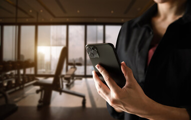 A man hand holding smart phone device in the fitness room view background