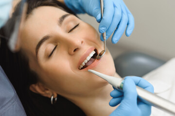 Female dentist examines the smile of a young woman after treatment, teeth brushing or enamel whitening. First person close-up shooting