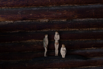 three human figures on the background of a log wall