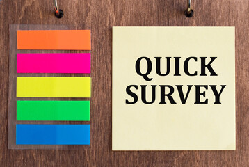 Quick Survey text on yellow note paper, near colored stickers on wooden background