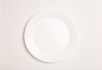 Empty white ceramic plate on white tablecloth background. Minimal concept