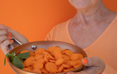 Female hands holding a pan full of sliced carrots ready to cook