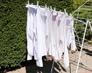 image of white curtains fabric after washing and drying with the sun outside a house near garden.