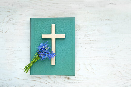 Cristianity cross, blue flowers and old bible books. symbol of Orthodox, Catholic, Protestant Christianity religion, faith in God, Church holiday concept. flat lay