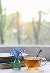 tea cup, spring blue flowers, old books on windowsill. romantic tea time, breakfast