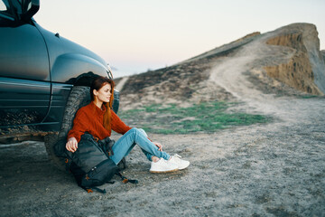 woman in the mountains on the sand with a backpack near the car top view