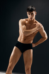 man with naked muscular body in the dark in shorts posing macho dark background