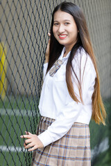 Asian young woman student holding Catch the net on the side of the stadium. Youth girl is smart and happy pose at college, Student education with learning girl in campus Concept school uniform.