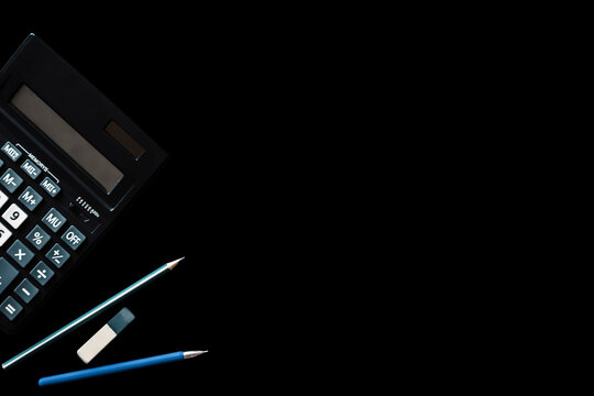 Calculator, pen, pencil and eraser are isolated on a black background with a blank space for text. Desktop concept, back to school.