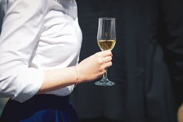 Details with the hands of a woman interacting at a classy event, while holding a glass of wine.