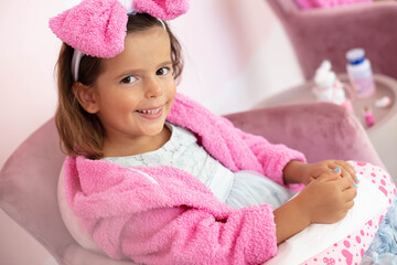 Little girl in spa center having a manicure.