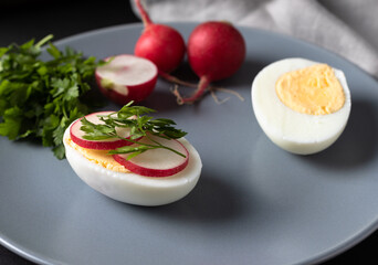 Closeup of boiled egg with fresh sliced radish. Diet food concept. Dish top view.