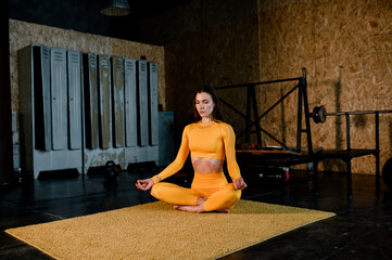 beautiful girl in a yellow sportswear is doing in yoga, breathing correctly. Modern sports hall