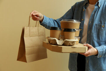 Woman hold delivery containers for takeaway food on beige background