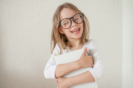 Little girl with glasses does homework, reads books. High quality photo