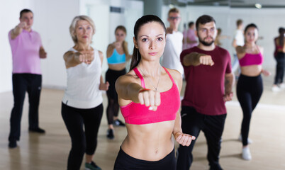 Active people of different ages practice sport dance in studio