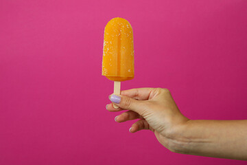 Female hand hold ice cream stick on pink background