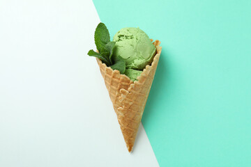 Cone of mint ice cream on two tone background